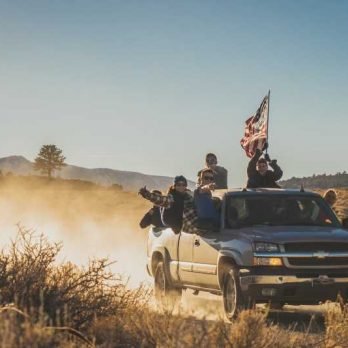 Group of young people driving a Chevrolet Silverado and raising a USA flag