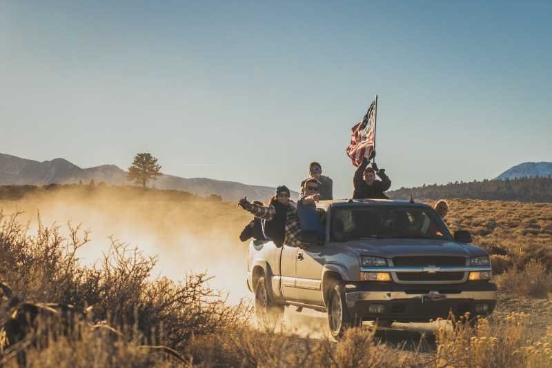 Group of young people driving a Chevrolet Silverado and raising a USA flag